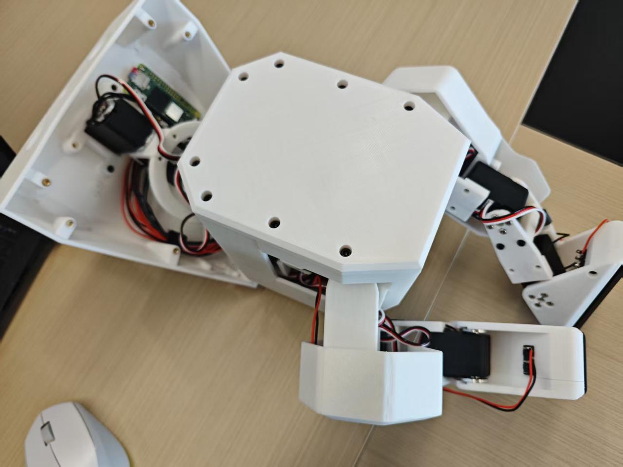 Hardware internals: 3D-printed PLA/PETG frame, servo actuators at each joint, Raspberry Pi onboard compute, custom PCB wiring harness.